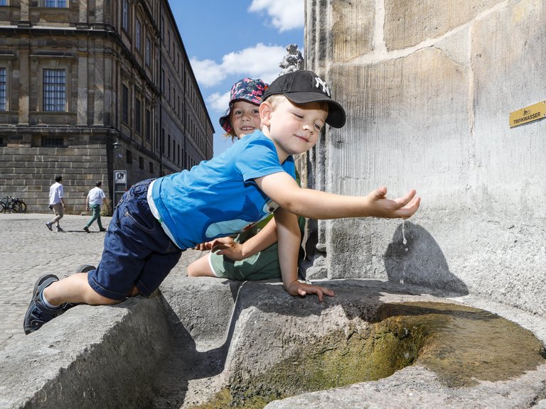 Junge spielt am Trinkwasserbrunnen