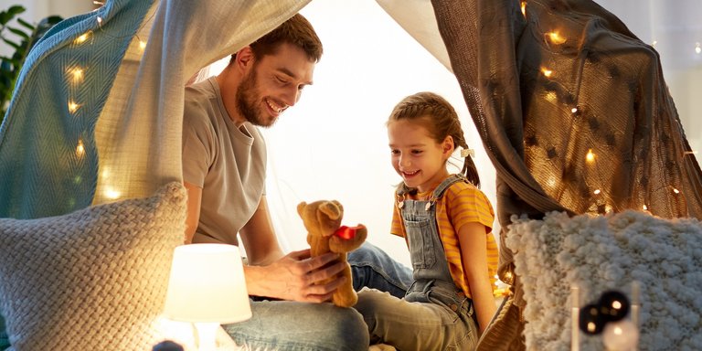 Vater und Tochter spielen im beleuchteten Zelt im Kinderzimmer
