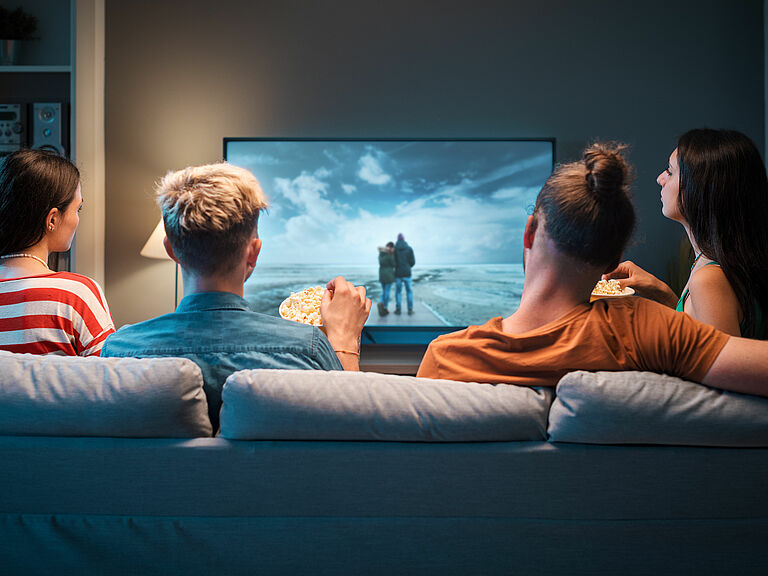 Gruppe junger Menschen schaut am Sofa einen Film