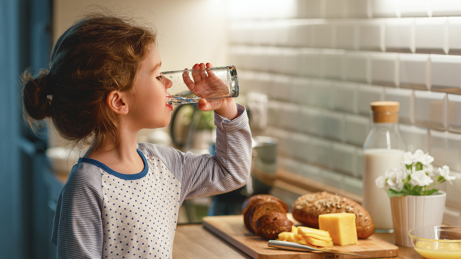 Kind trinkt Wasser in der Küche zum Frühstück