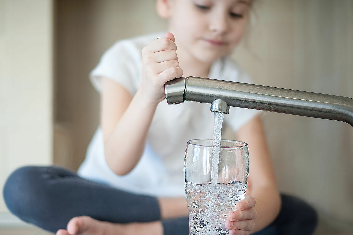 Kind zapft Trinkwasser aus Wasserhahn