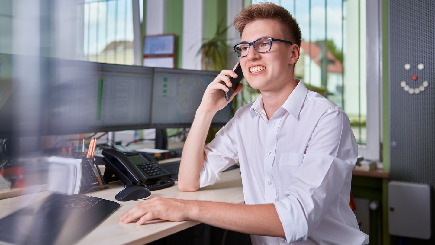 Junger Auszubildender in der Leitstelle der Stadtbusse am Telefon Junger Auszubildender in der Leitstelle der Stadtbusse am Telefon