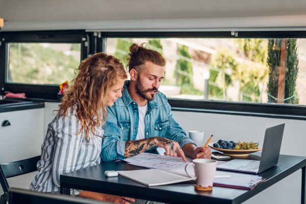 Frau und Mann am Tisch mit Plänen und Laptop