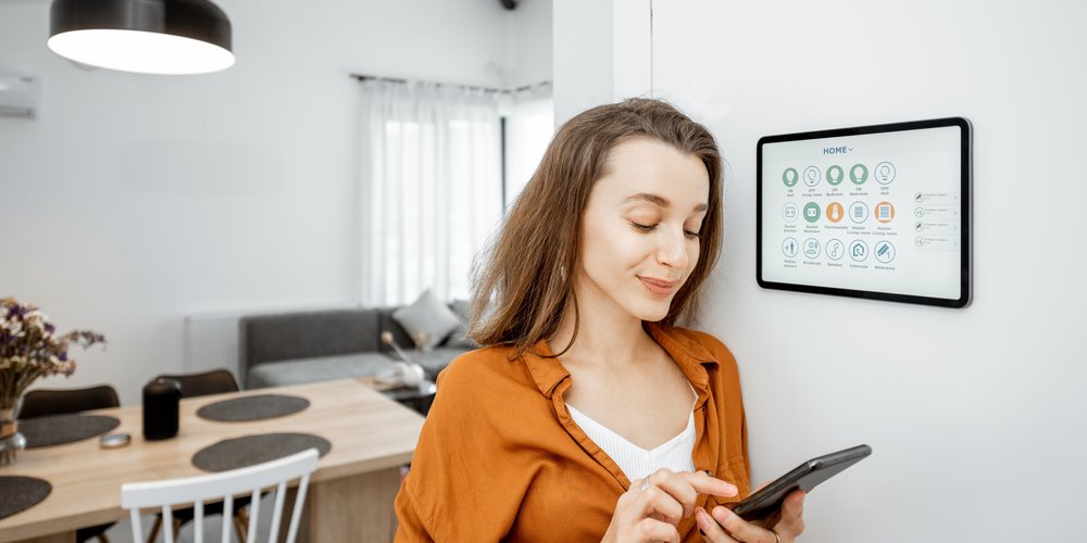 Frau steuert Smart Home Display mit Smartphone im Raum