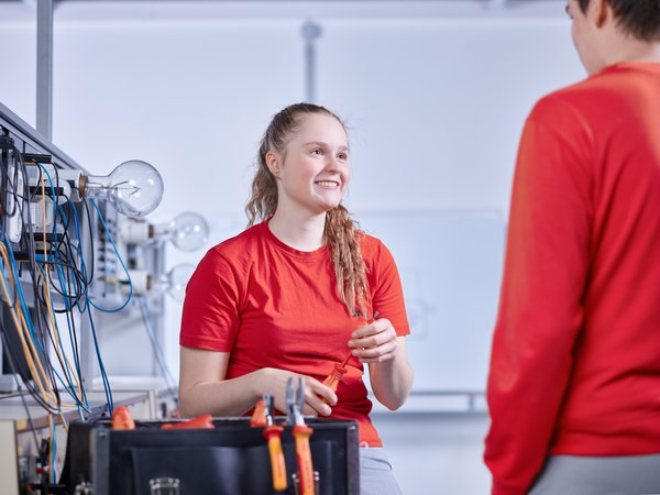 Azubi Elektrikerin Lisa Schmitt Auszubildende unterhält sich mit einem Kollegen