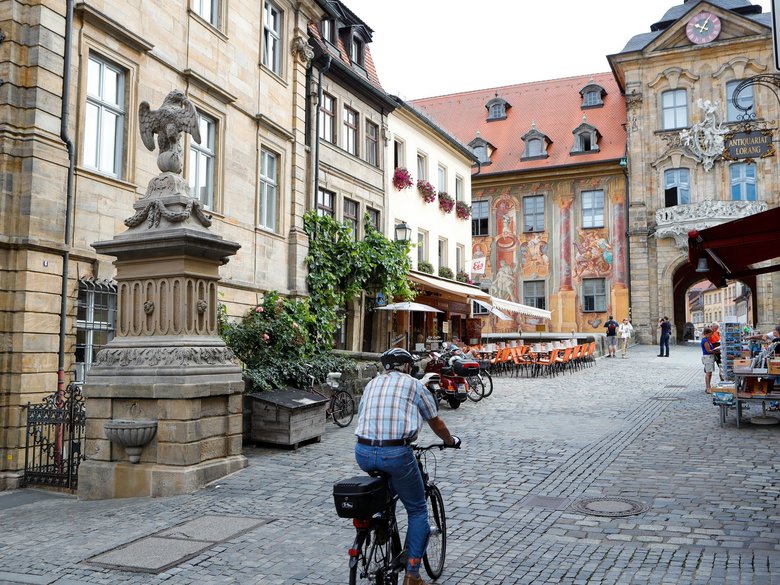 Mann fährt auf einem Fahrrad vor dem Trinkwasserbrunnen