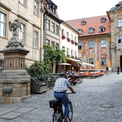 Mann fährt auf einem Fahrrad vor dem Trinkwasserbrunnen
