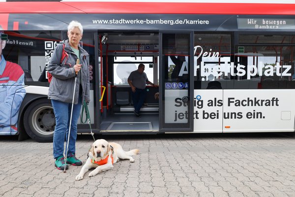 Blinde Frau mit Assistenzhunde vor dem Bus