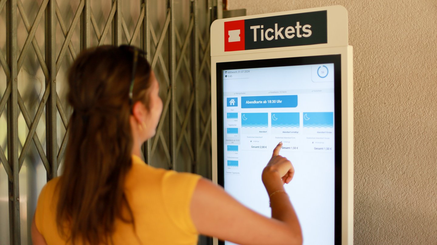 Frau bedient Ticketautomaten im Stadionbad