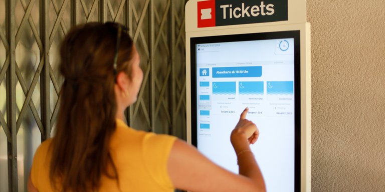Frau bedient Ticketautomaten im Stadionbad