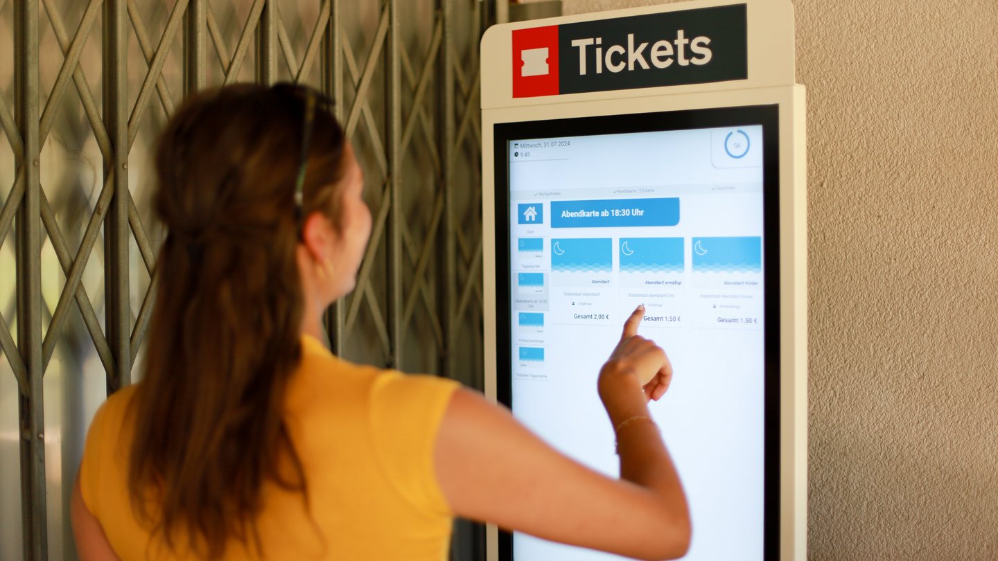 Frau bedient Ticketautomaten im Stadionbad