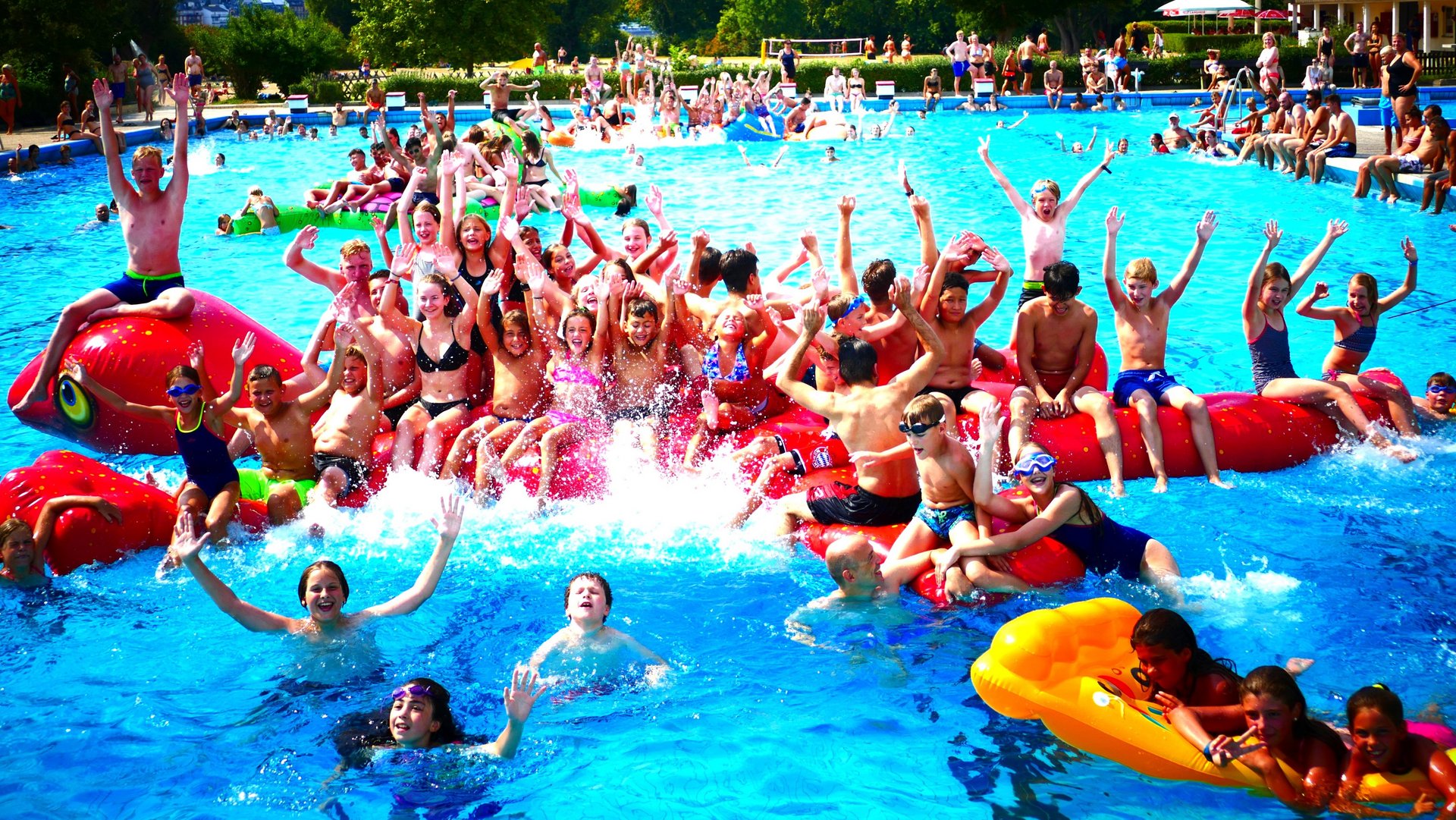 Kinder haben Spaß mit einem großen Schwimmtier bei einer Pool-Party