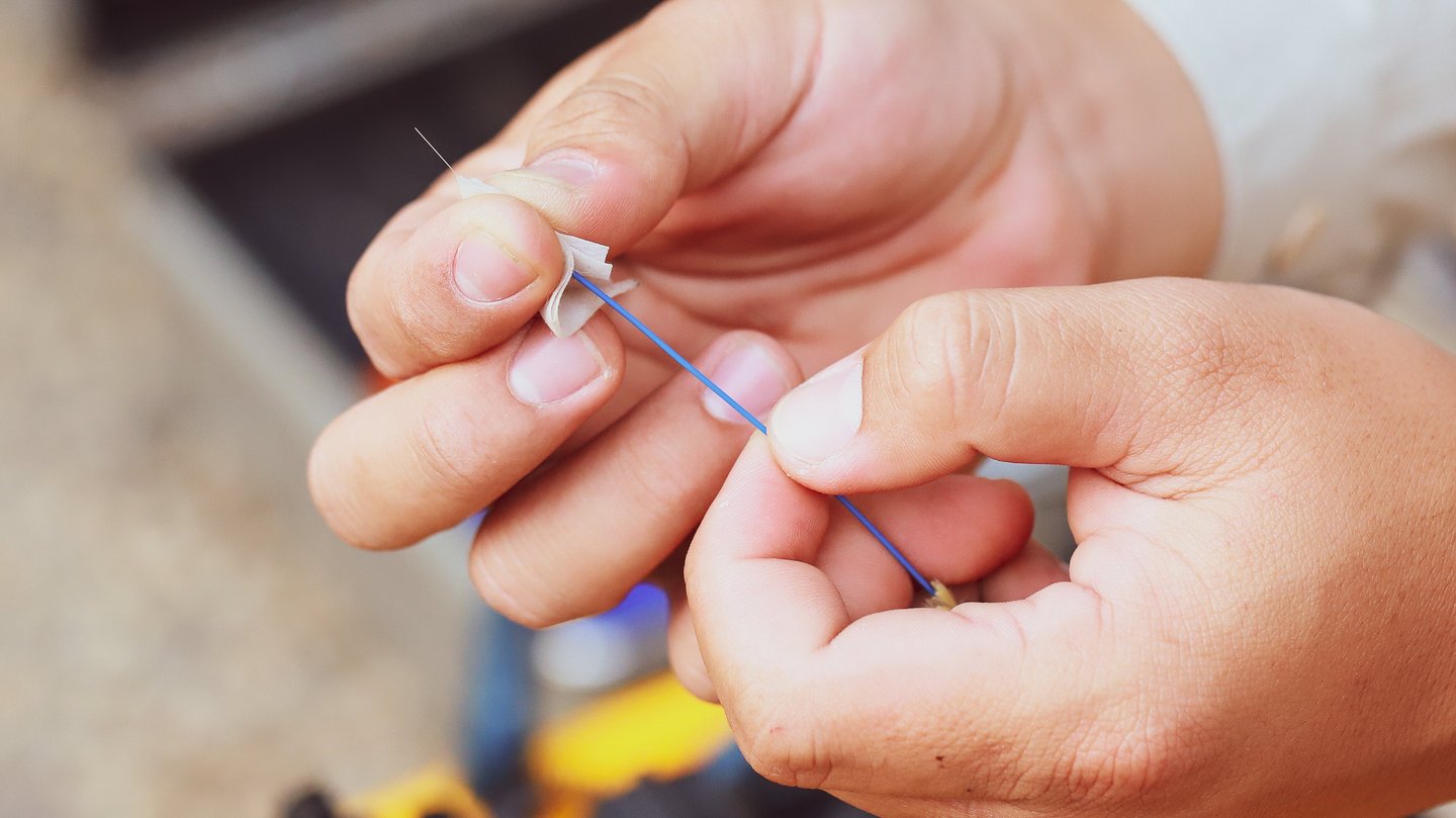 Einzelne Glasfaser wird in Händen gehalten