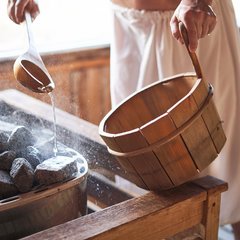 Holzeimer und Holzkelle in einer Sauna beim Aufguss