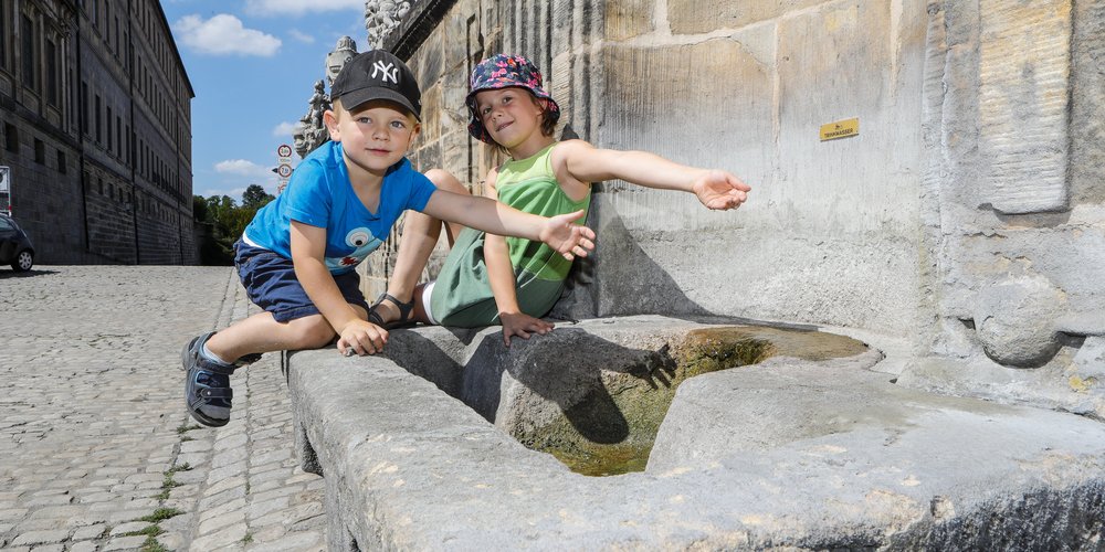 Kinder trinken aus Brunnen