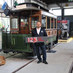 Historischer Stadtverkehr Bamberg Vereinsausflug ins Historische Straßenbahndepot St. Peter Nürnberg Mann mit Schild "125 Jahre ÖPNV Bamberg" vor historischer Straßenbahn im Straßenbahndepot St. Peter in Nürnberg