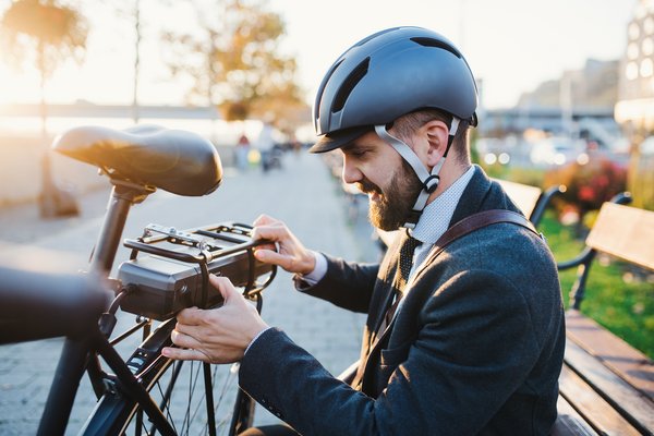 Hipster businessman commuter setting up electric bicycle in city.