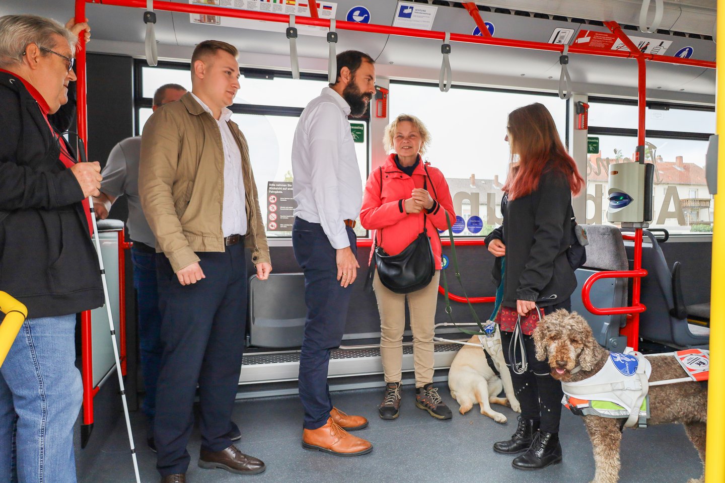 Menschen mit Einschränkung und Assitenzhunden im Bus mit Dialog mit Stadtwerke-Mitarbeitenden
